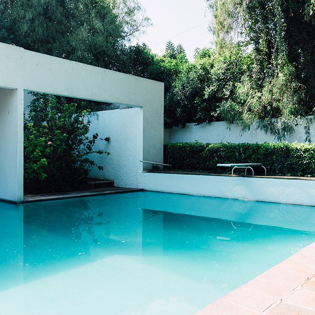 This is a photo of a swimming pool, featuring white block-like architecture surrounding it.