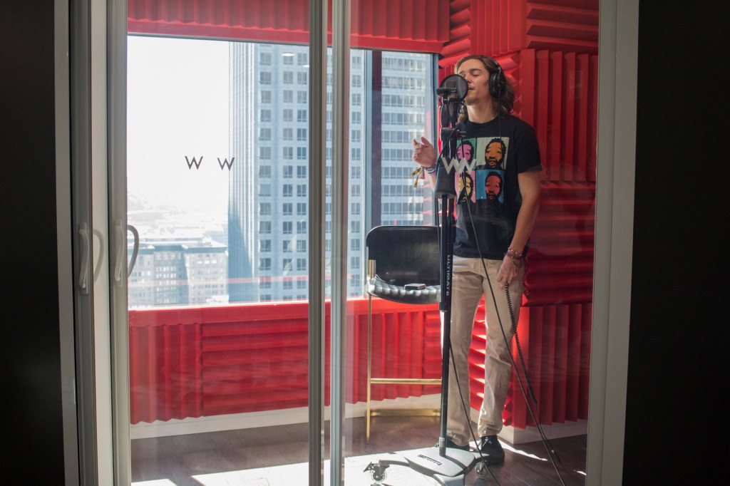 This is a photo of a student in the W Seattle Sound Suite. He is recording vocals.